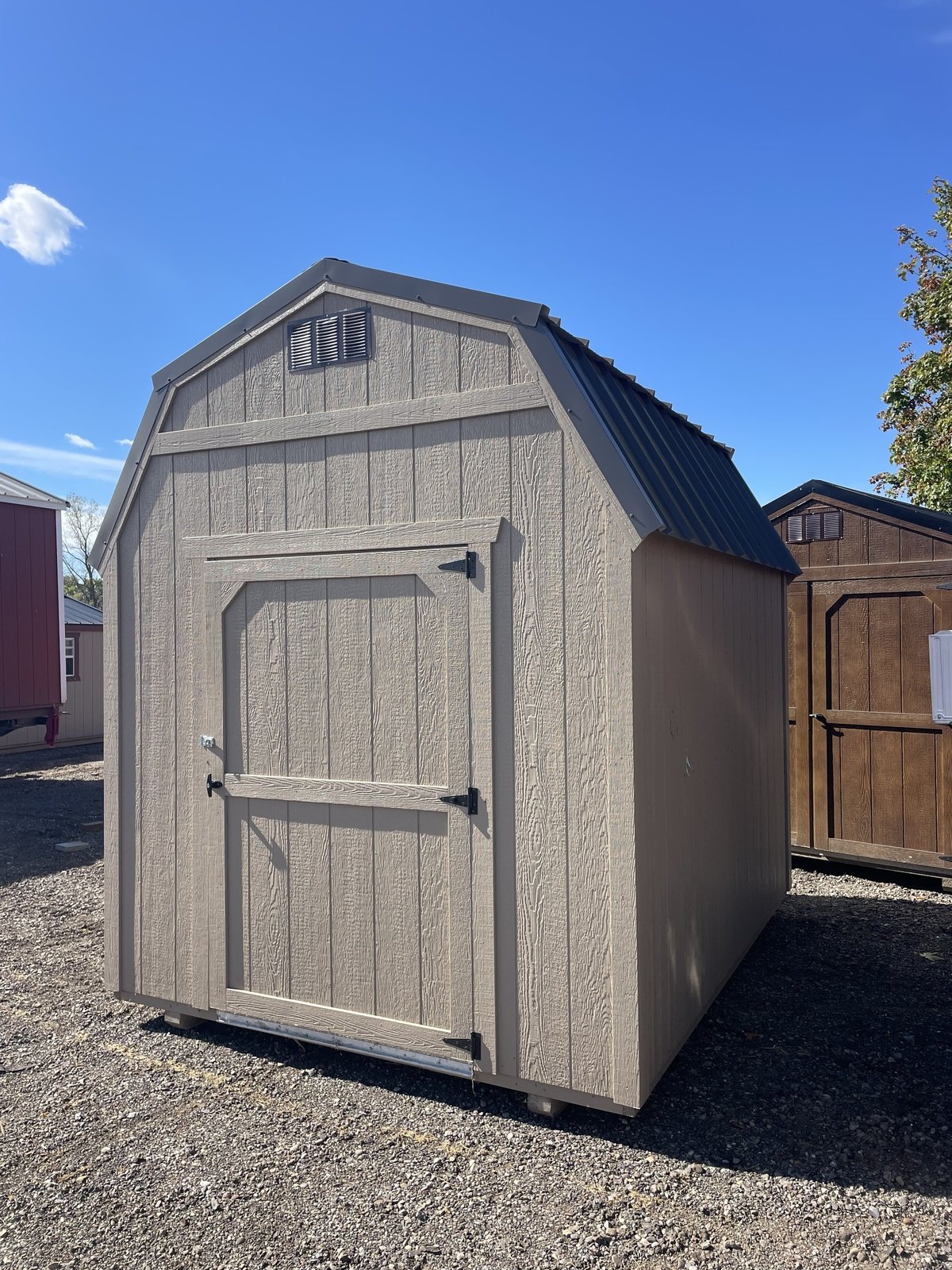 Millcraft gambrel shed with tan siding and a dark metal roof